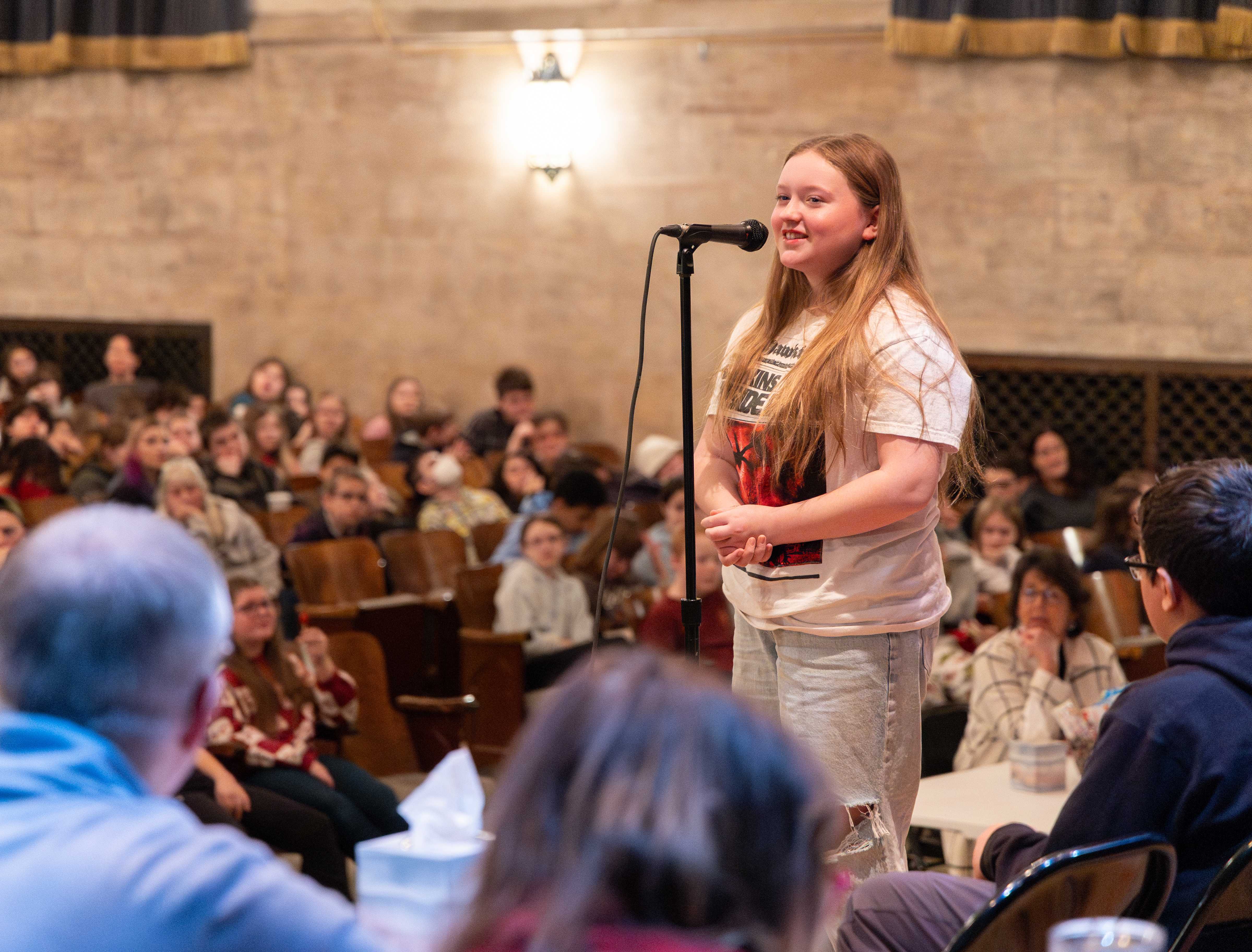 A student smiles as she spells a word at the microphone